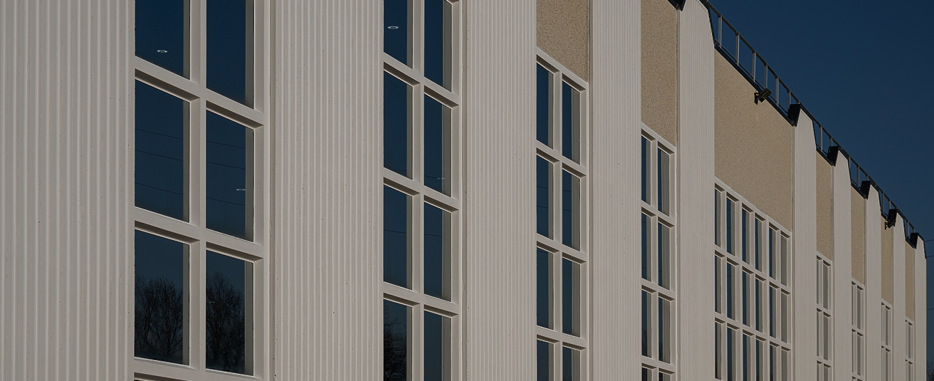 Detailed architectural view of IMTE’s headquarters windows, reflecting the surrounding landscape under clear blue skies, symbolizing transparency and sustainability.